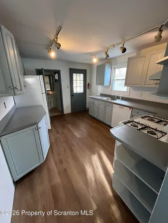 a view of a kitchen with a sink and dishwasher a stove top oven with wooden floor