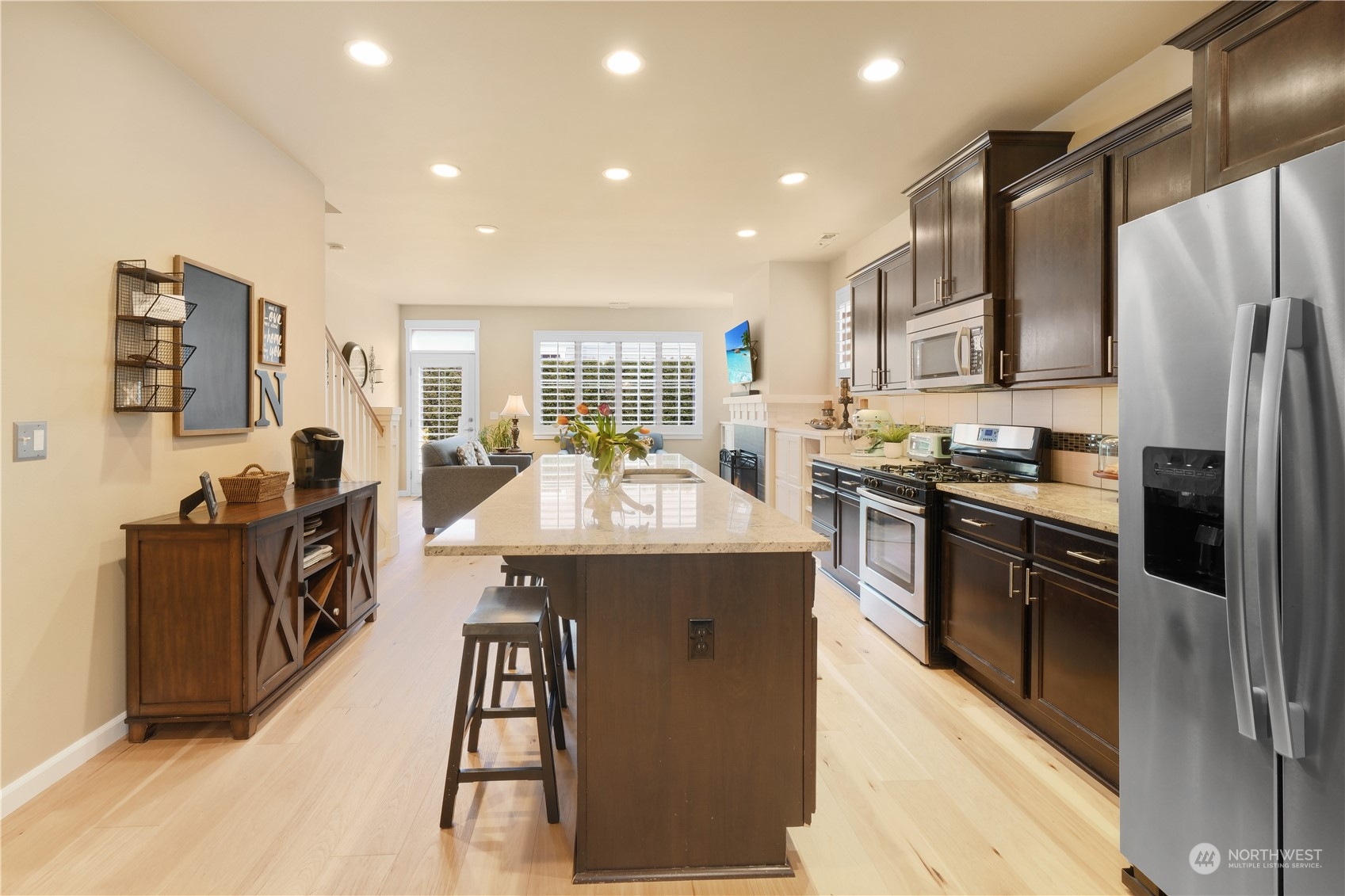 21907 37th Drive Southeast, Unit 30 Bothell, WA 98021 - Photo 5 of 27 a kitchen with stainless steel appliances kitchen island granite countertop a refrigerator a sink dishwasher a stove and a dining table with wooden floor