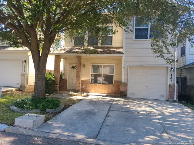 a view of a house with a yard and large tree