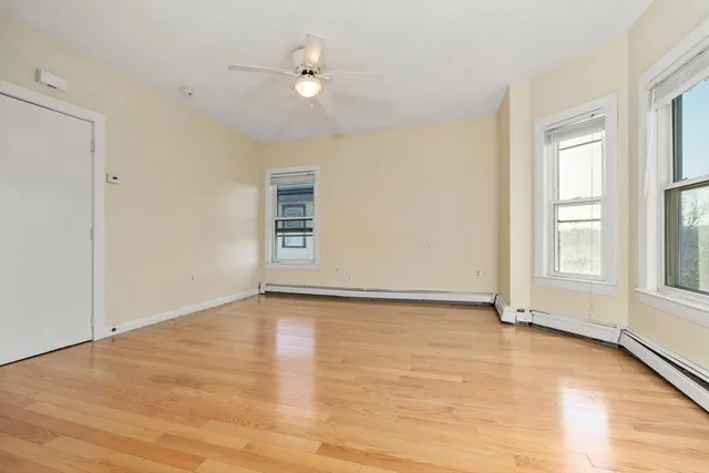 a view of an empty room with a window and wooden floor