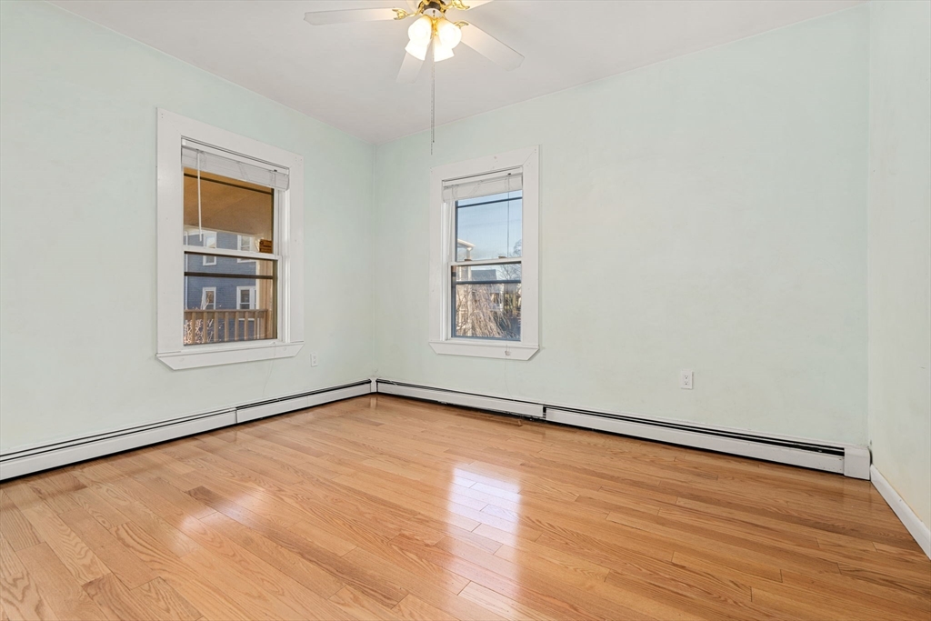 3266 Washington Street, Unit 3F Boston, MA 02130 - Photo 10 of 20 an empty room with wooden floor chandelier fan and windows