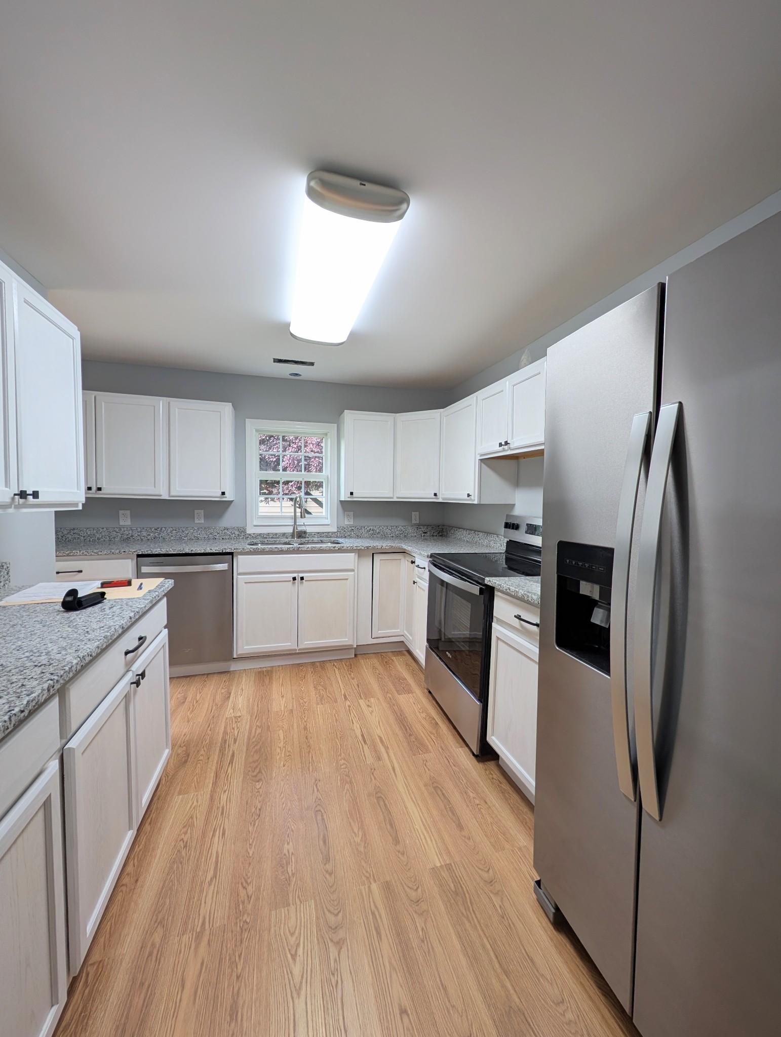 406 Horton Street Decherd, TN 37324 - Photo 13 of 24 a large kitchen with stainless steel appliances granite countertop a stove top oven a refrigerator and white cabinets with wooden floor