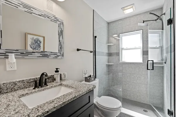 a bathroom with a granite countertop sink a toilet and a mirror