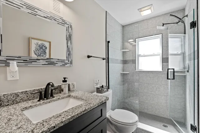 a bathroom with a granite countertop sink a toilet and a mirror