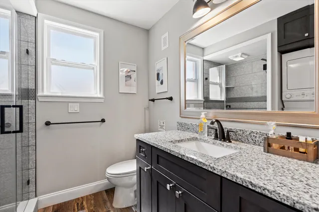 a bathroom with a granite countertop sink a toilet and a mirror