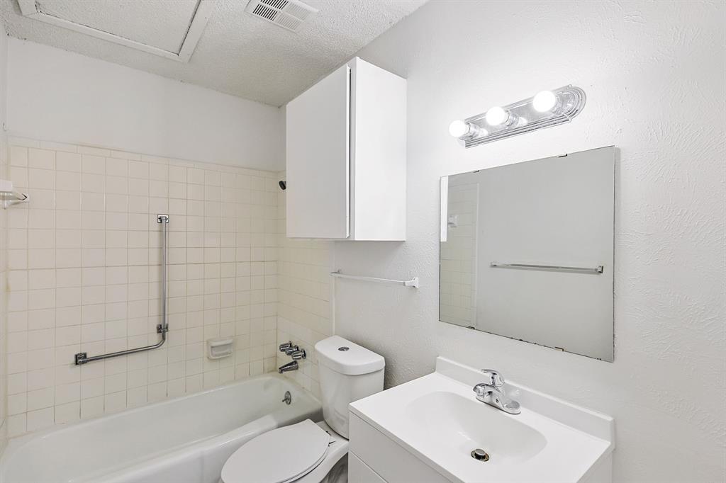 2637 West Randol Mill Road, Unit 2639D Arlington, TX 76012 - Photo 2 of 15 Bathroom featuring a white bathtub, ceramic wall tiles, toilet, and a vanity with an integrated sink