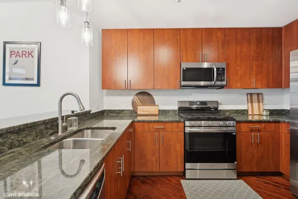 a kitchen with granite countertop a stove top oven microwave and sink