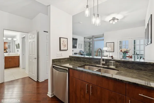 a kitchen with stainless steel appliances granite countertop a sink a stove and a wooden floors