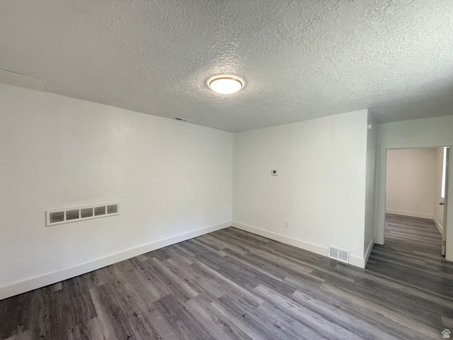548 27th Street Ogden, UT 84403 - Photo 9 of 13 Unfurnished room featuring dark wood-type flooring and a textured ceiling