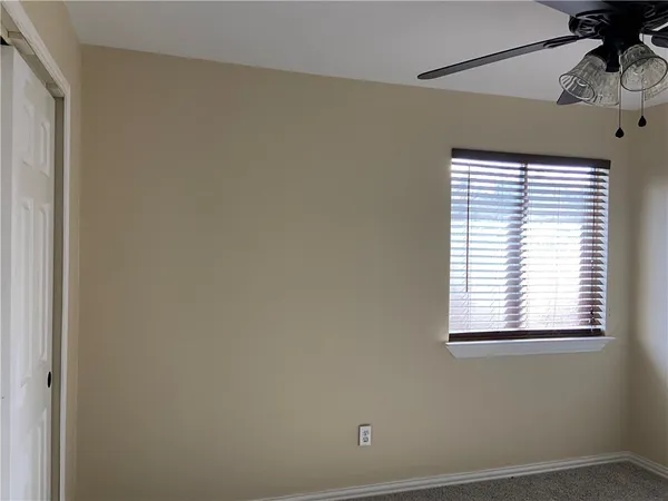 an empty room with a window and a ceiling fan