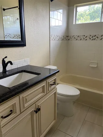 a bathroom with a granite countertop sink a toilet and shower