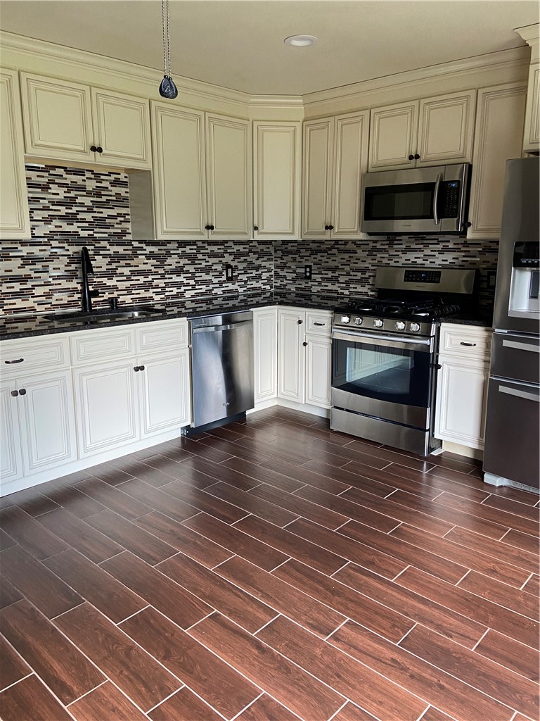 1257 Pine Portage Loop Leander, TX 78641 - Photo 10 of 32 Kitchen with stainless steel appliances, wood tiled floors, dark stone countertops, decorative backsplash,