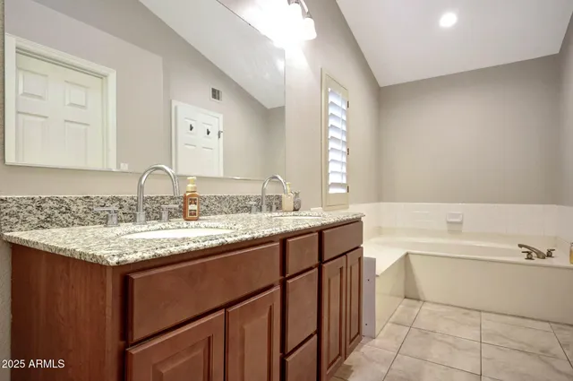 a bathroom with a granite countertop sink and a bathtub