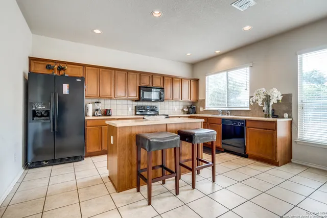 a kitchen with granite countertop a refrigerator and a stove top oven