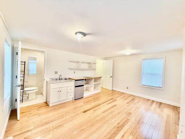 a large white kitchen with granite countertop a stove top oven sink and cabinets