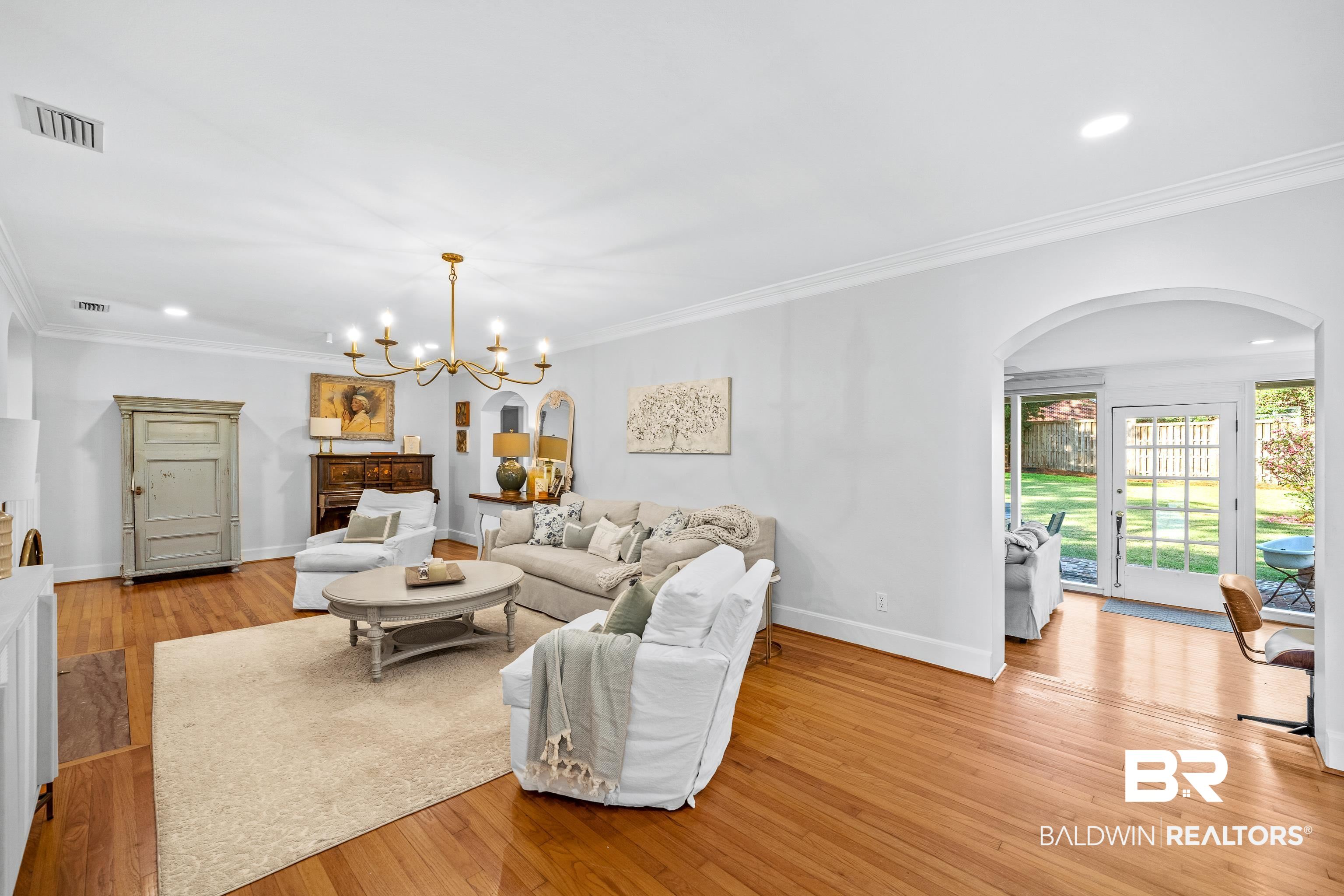 141 Myrtlewood Lane Mobile, AL 36608 - Photo 16 of 44 Living room featuring an inviting chandelier, baseboards, arched walkways, light wood finished floors, and visible vents