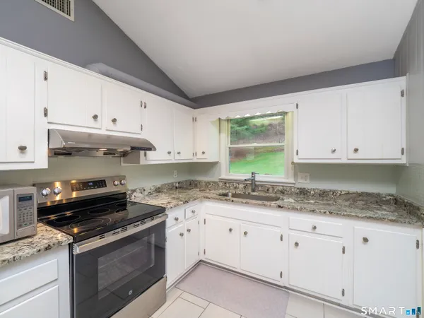 a kitchen with granite countertop white cabinets and a stove top oven