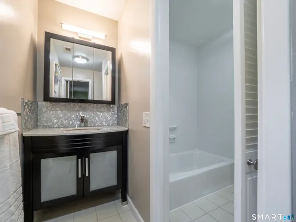 a bathroom with a granite countertop sink mirror and bathtub