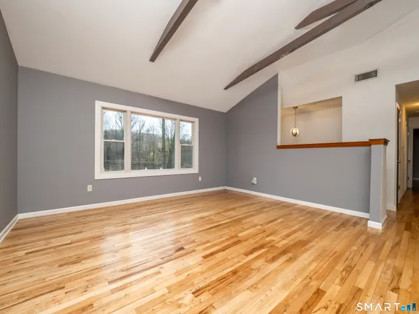 a view of an empty room with wooden floor and a window