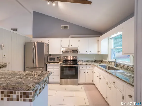 a kitchen with stainless steel appliances granite countertop a stove sink and cabinets