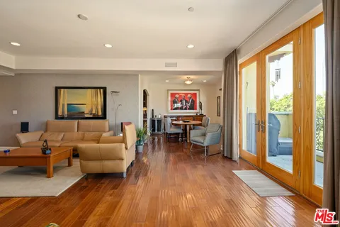 a living room with furniture a large window and wooden floor