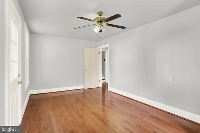 an empty room with wooden floor and ceiling fan