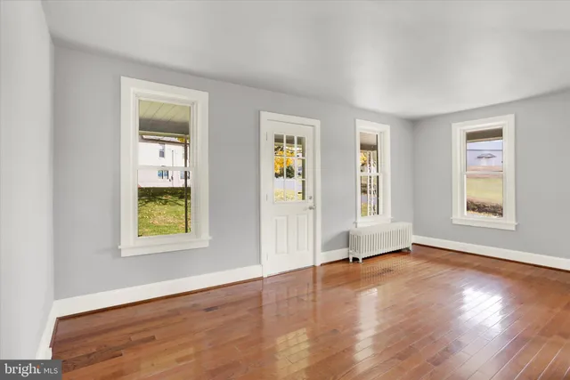 a view of an empty room with window and wooden floor