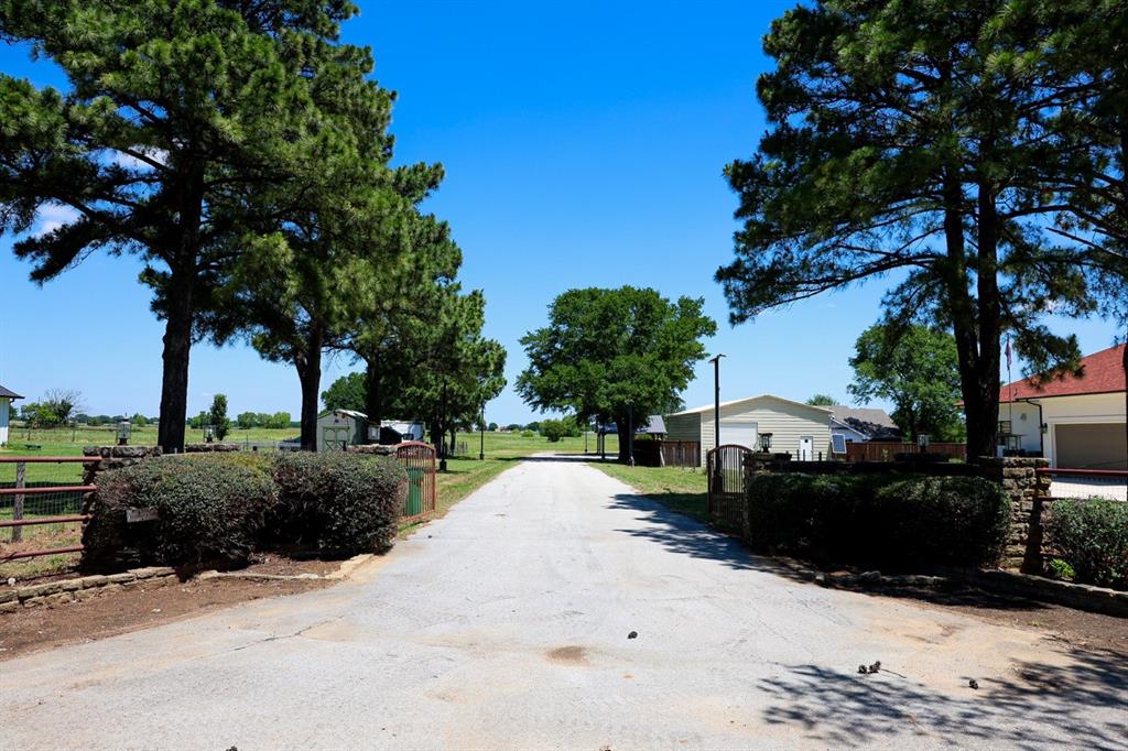 10575 Friendship Road Pilot Point, TX 76258 - Photo 2 of 32 Gated entry with stone pillars and mature landscaping leading to an expansive property