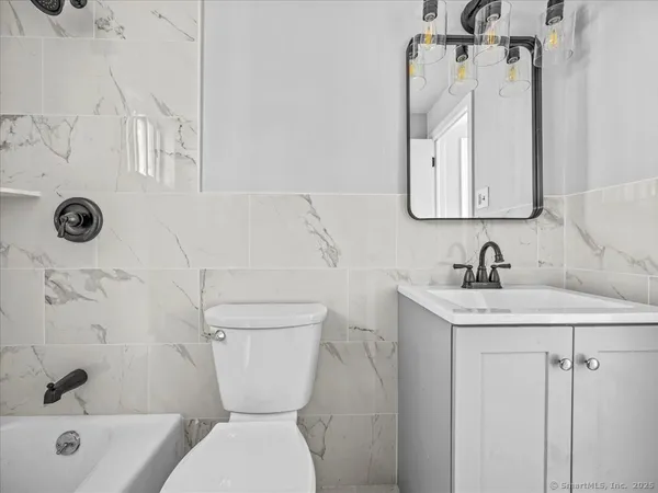 a bathroom with a granite countertop toilet sink and mirror