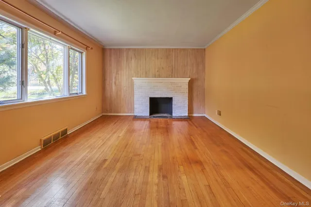 a view of empty room with wooden floor and fireplace