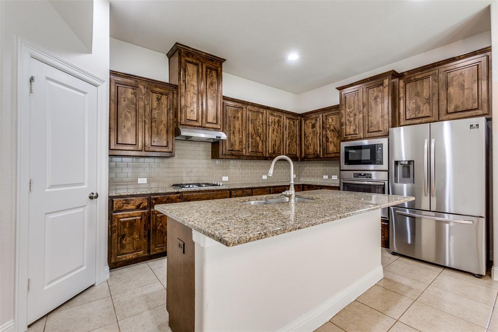 12618 Akenside Road Frisco, TX 75035 - Photo 11 of 31 Kitchen with sink, stainless steel appliances, tasteful backsplash, and an island with sink
