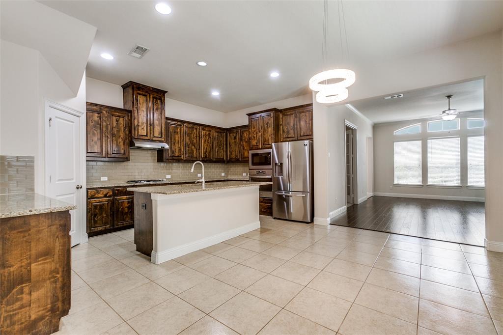 12618 Akenside Road Frisco, TX 75035 - Photo 8 of 31 Kitchen with light wood-type flooring, backsplash, dark brown cabinetry, a kitchen island with sink, and stainless steel appliances