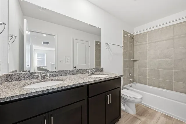 a bathroom with a granite countertop bathtub sink double vanity and mirror