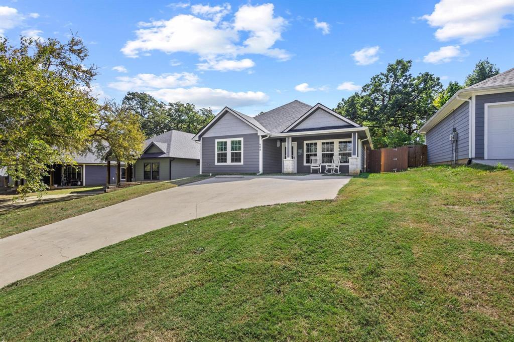 608 East Shepherd Street Denison, TX 75021 - Photo 5 of 31 Contemporary residence featuring a dark gray facade with white trim, a covered front porch, an attached garage, a concrete driveway, and established landscaping