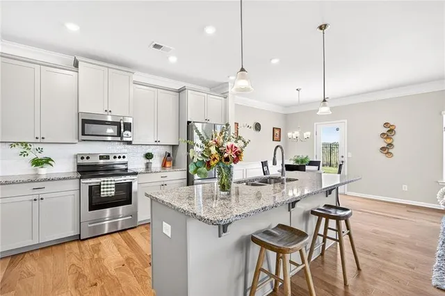 a kitchen with stainless steel appliances kitchen island granite countertop a stove top oven a sink a dining table and chairs with wooden floor