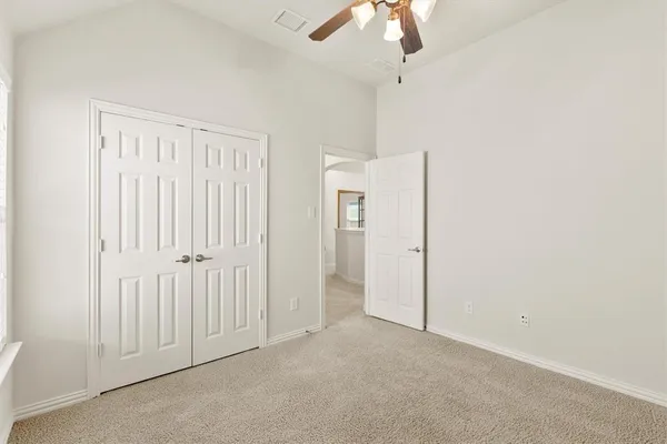 an empty room with windows and ceiling fan
