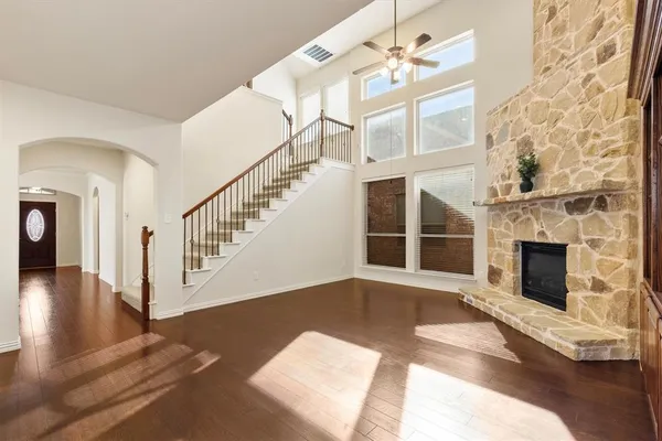 a view of an empty room with wooden floor and a fireplace