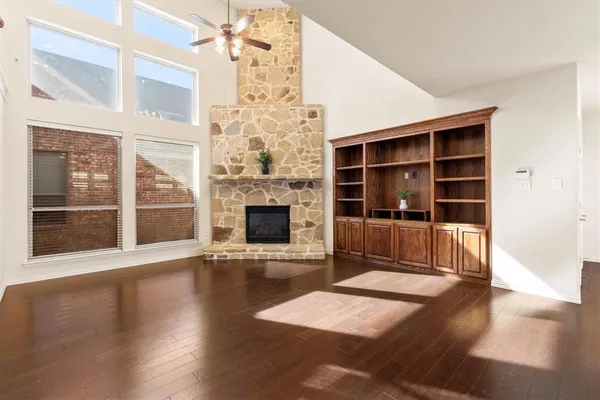 a view of an empty room with wooden floor and a fireplace