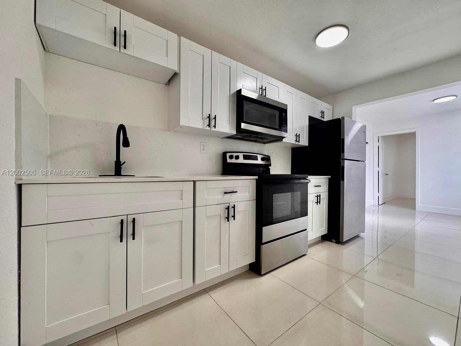 541 East 38th Street Hialeah, FL 33013 - Photo 5 of 14 a kitchen with white cabinets stainless steel appliances and a sink