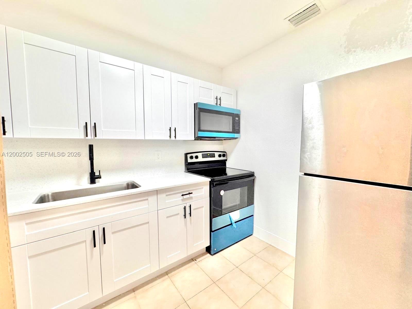 541 East 38th Street Hialeah, FL 33013 - Photo 6 of 14 a kitchen with white cabinets and refrigerator