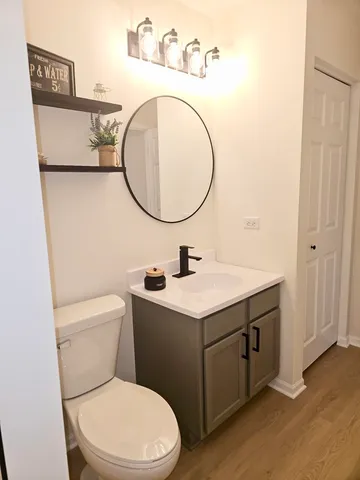 a view of a white house in front of a big yard with plants and large trees