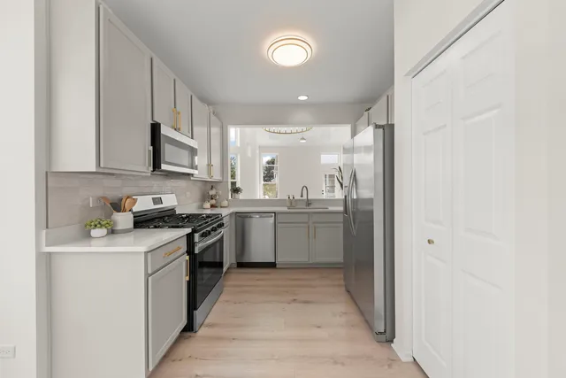 a kitchen with a sink cabinets stainless steel appliances and a window