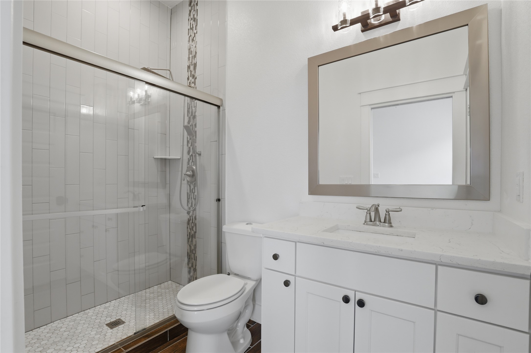 133 Greg Lane Jarrell, TX 76537 - Photo 20 of 24 Bathroom featuring a glass-enclosed shower with white vertical tile, a decorative vertical mosaic accent, and a white hexagonal tile floor