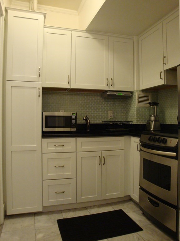 21 Beacon Street, Unit 6D Boston, MA 02108 - Photo 8 of 13 a kitchen with white cabinets and black appliances