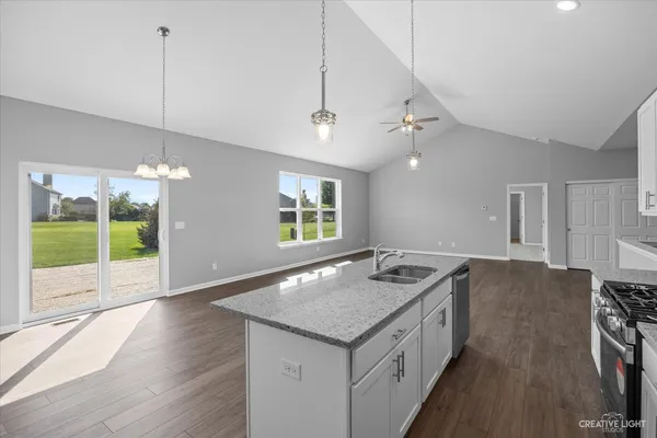 a kitchen with a stove a faucet a chandelier and wooden floor