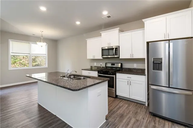 a kitchen with stainless steel appliances granite countertop a refrigerator a sink dishwasher a stove and a refrigerator with wooden floor