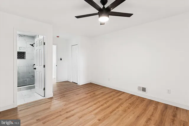 a view of a room with wooden floor and a ceiling fan