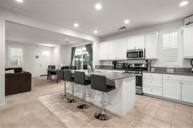 a kitchen with stainless steel appliances kitchen island granite countertop a refrigerator a stove a sink dishwasher with a dining table and chairs