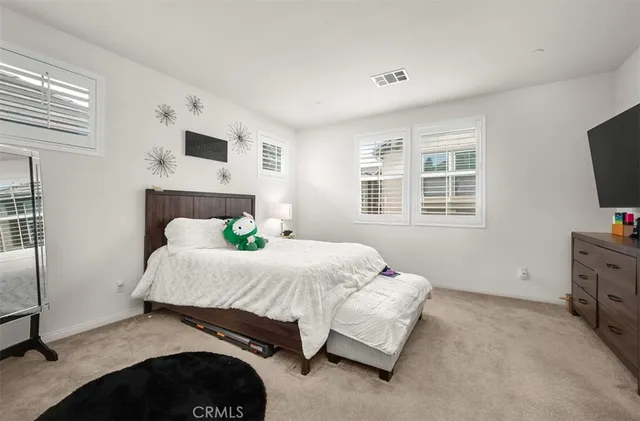 a bedroom with a bed and flat tv screen on the dresser