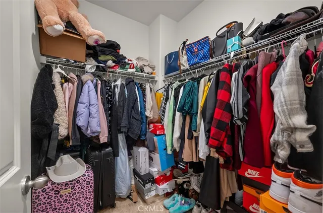 a view of walk in closet with clothes and shoes